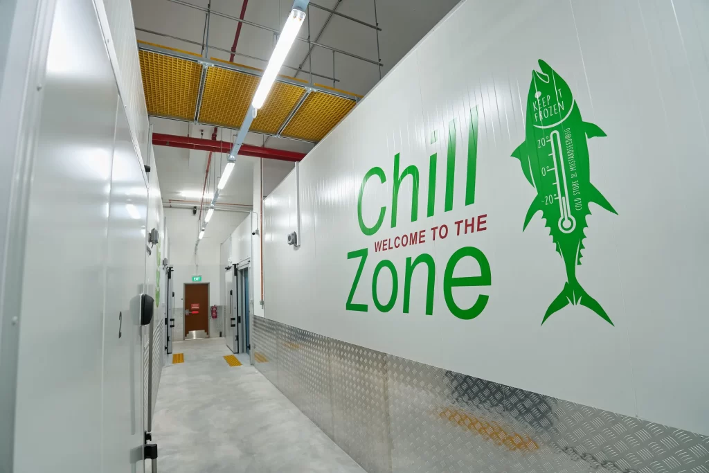 Corridor in MustardSeed@SG ColdStore with green and red fish and 'Welcome to the Chill Zone' decal on wall